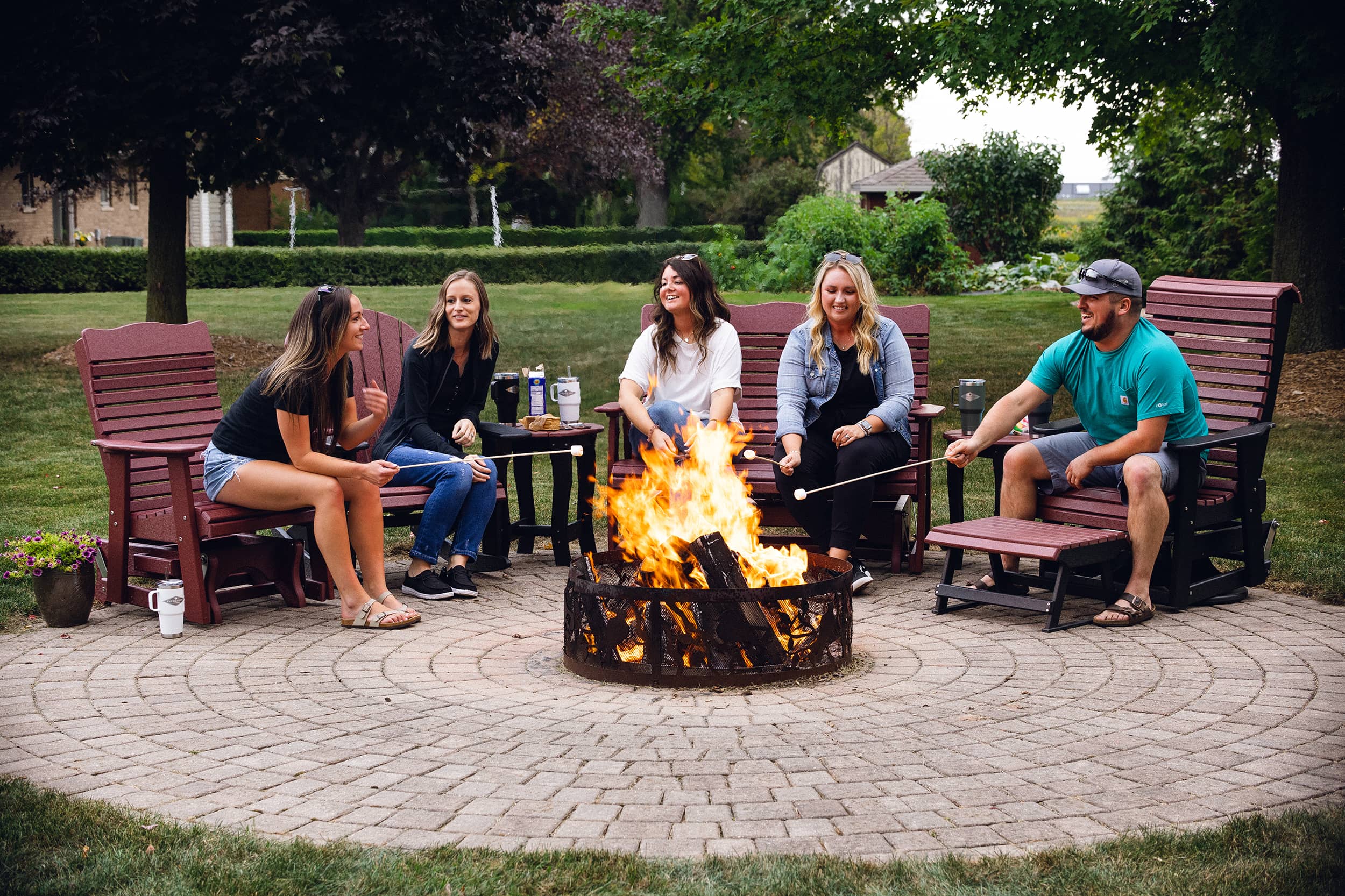 A group of people sitting around a fire and sitting in Evergreen Outdoor chairs